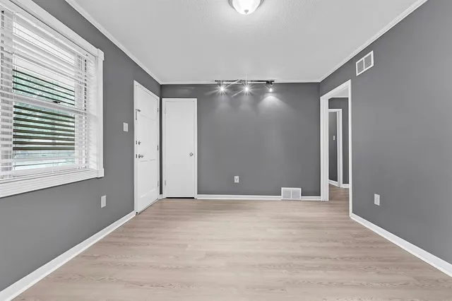 a view of an empty room with window and wooden floor