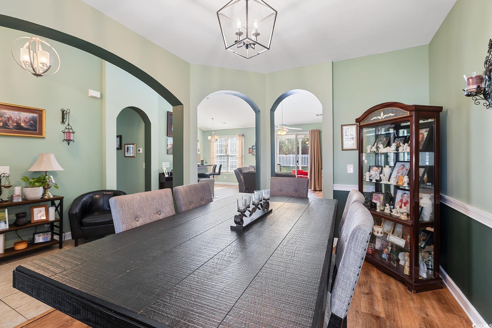 720 Gazania Lane Myrtle Beach, SC 29579 - Photo 9 of 32 Dining space featuring a chandelier, arched walkways, and wood finished floors