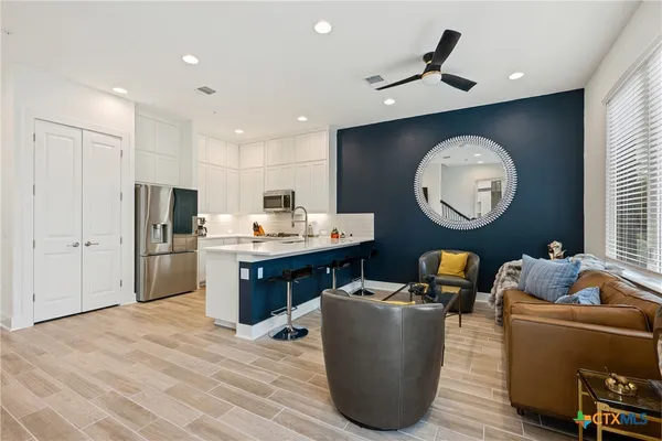 a living room with couches kitchen view and a refrigerator