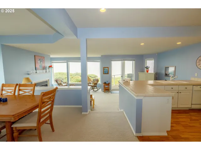 a dining hall with stainless steel appliances kitchen island granite countertop a table chairs and a living room view