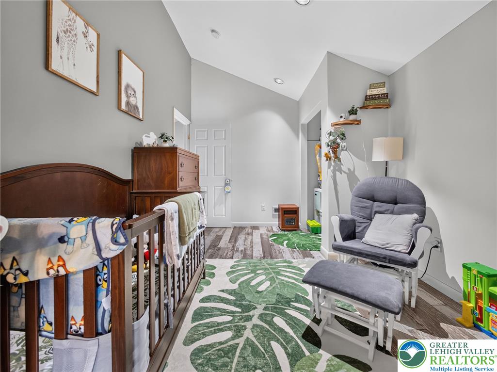 2628 Levans Road Coplay, PA 18037 - Photo 33 of 54 A comforting nursery features a crib, rocker, and hardwood floors beneath a vaulted ceiling.