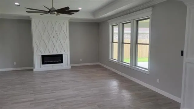 an empty room with wooden floor fan and windows