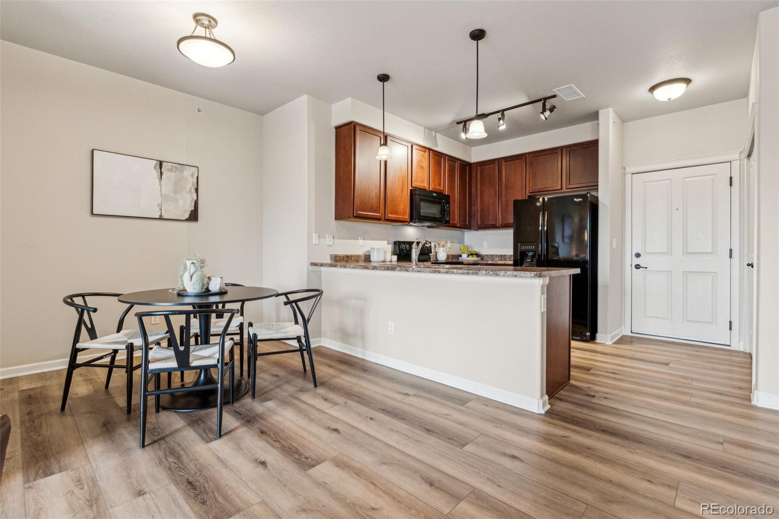 1062 Rockhurst Drive, Unit 401 Highlands Ranch, CO 80129 - Photo 18 of 41 a kitchen with a table chairs refrigerator and microwave