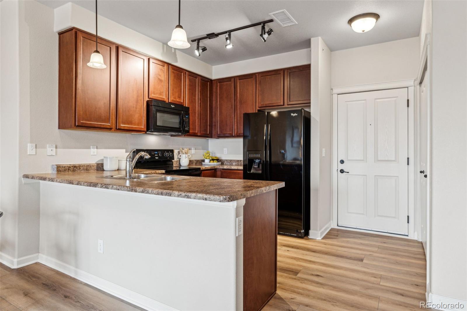 1062 Rockhurst Drive, Unit 401 Highlands Ranch, CO 80129 - Photo 3 of 41 a kitchen with stainless steel appliances granite countertop a refrigerator a stove a sink and a microwave with wooden floor