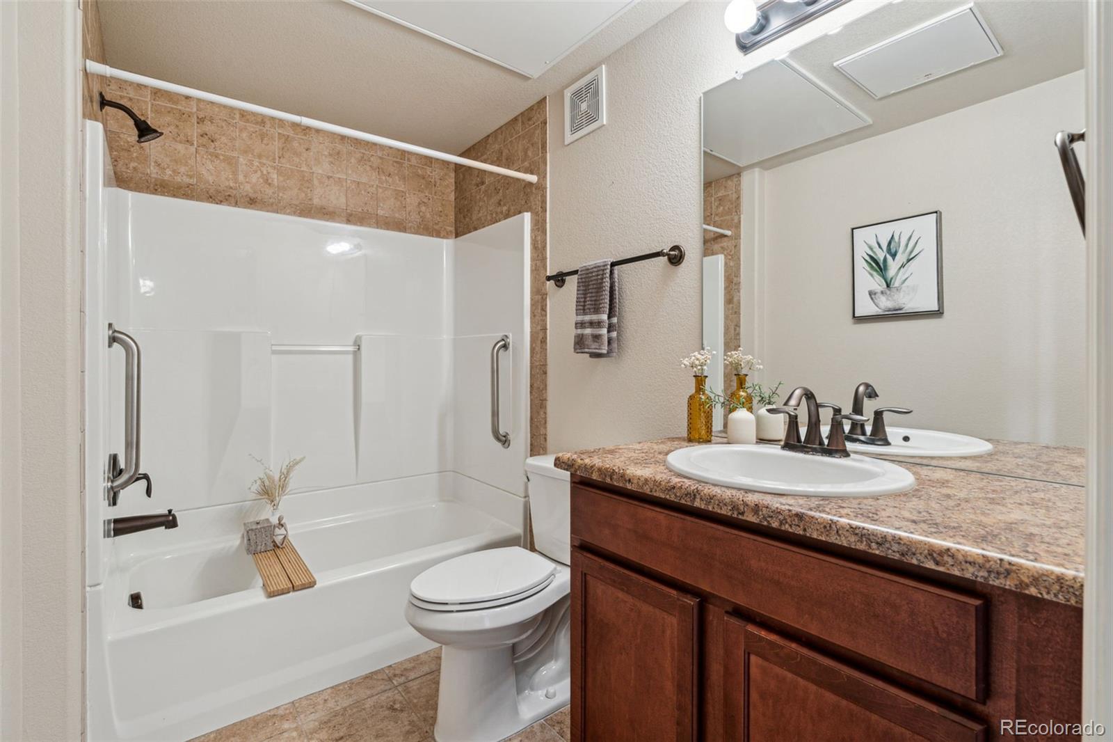 1062 Rockhurst Drive, Unit 401 Highlands Ranch, CO 80129 - Photo 31 of 41 a bathroom with a granite countertop sink a toilet a mirror and shower