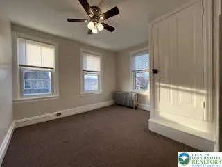 an empty room with windows and fan