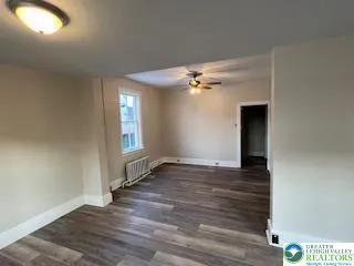 a view of an empty room with window and wooden floor