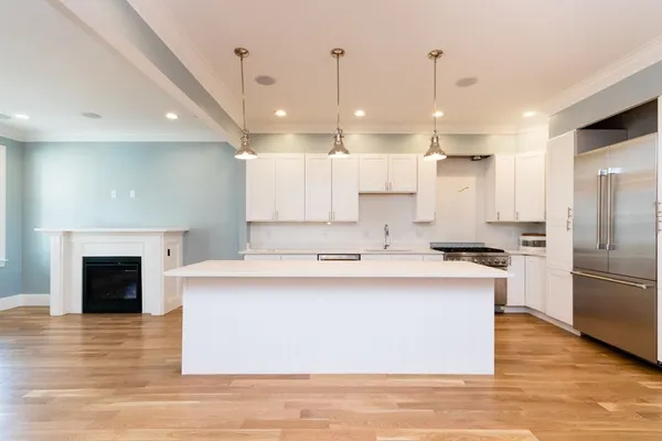 a large kitchen with kitchen island a stove a sink a refrigerator and a fireplace