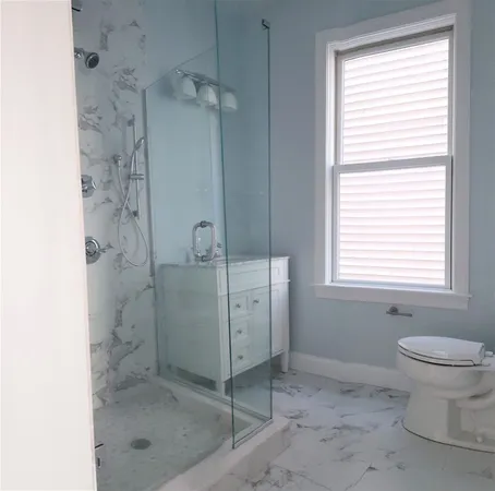 a bathroom with a granite countertop sink a toilet and shower