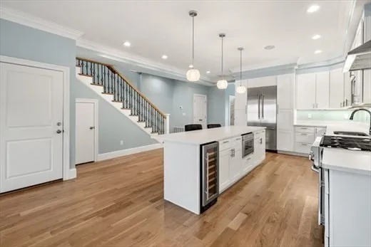 a large white kitchen with a stove a sink dishwasher and a refrigerator with wooden floor