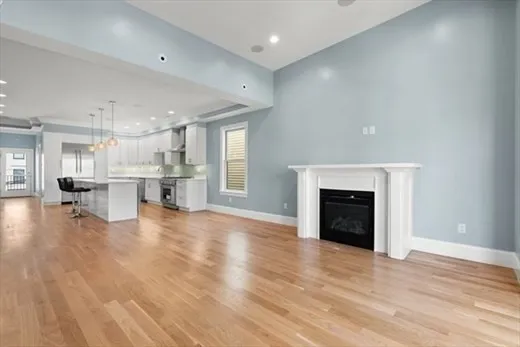 a view of kitchen and empty room with wooden floor