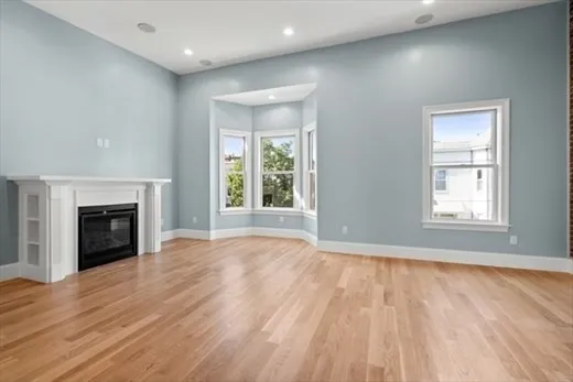 wooden floor fireplace and windows in an empty room