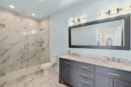a bathroom with a granite countertop sink a toilet a mirror and shower