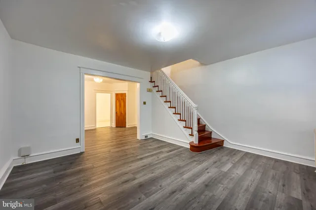 a view of an empty room with wooden floor and stairs