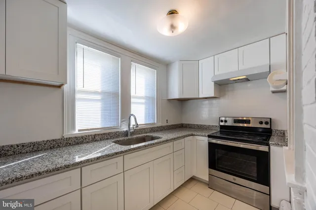 a kitchen with granite countertop a stove sink and cabinets