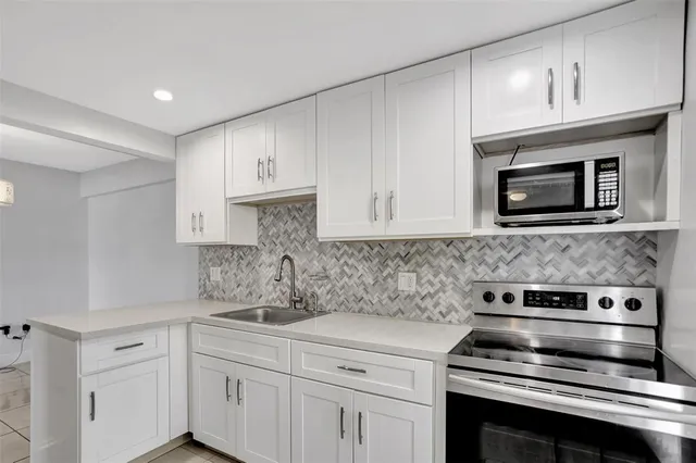 a kitchen with granite countertop white cabinets and stainless steel appliances