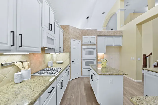 a kitchen with granite countertop a sink stove and cabinets