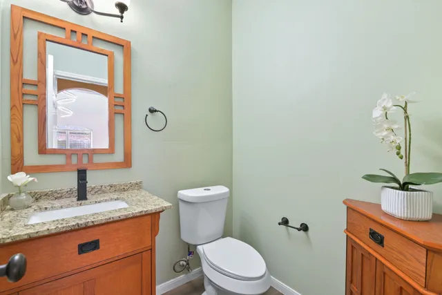 a bathroom with a granite countertop sink toilet and mirror