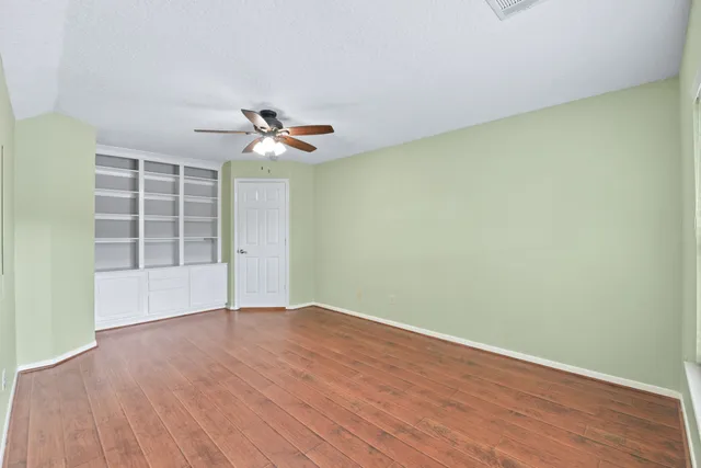 an empty room with wooden floor and a ceiling fan