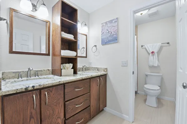 a bathroom with a granite countertop sink toilet and mirror