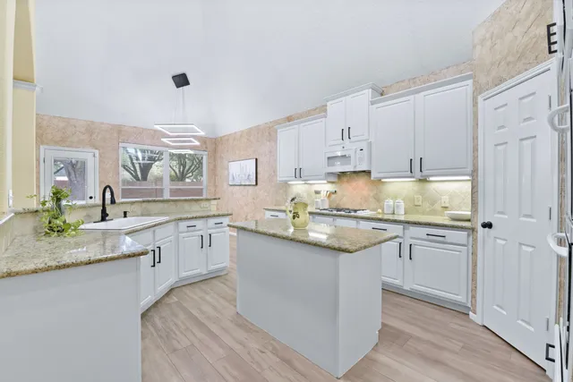 a kitchen with granite countertop cabinets sink and white appliances