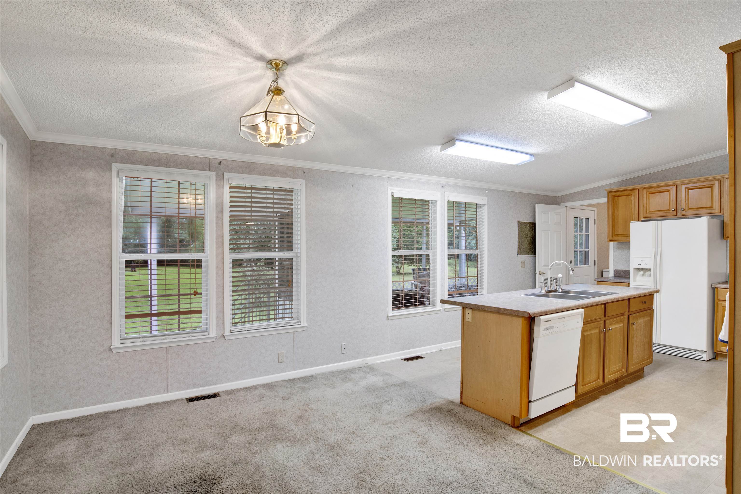 25700 County Road 71 Robertsdale, AL 36567 - Photo 7 of 40 Kitchen with white appliances, ornamental molding, a center island with sink, a textured ceiling, and light countertops