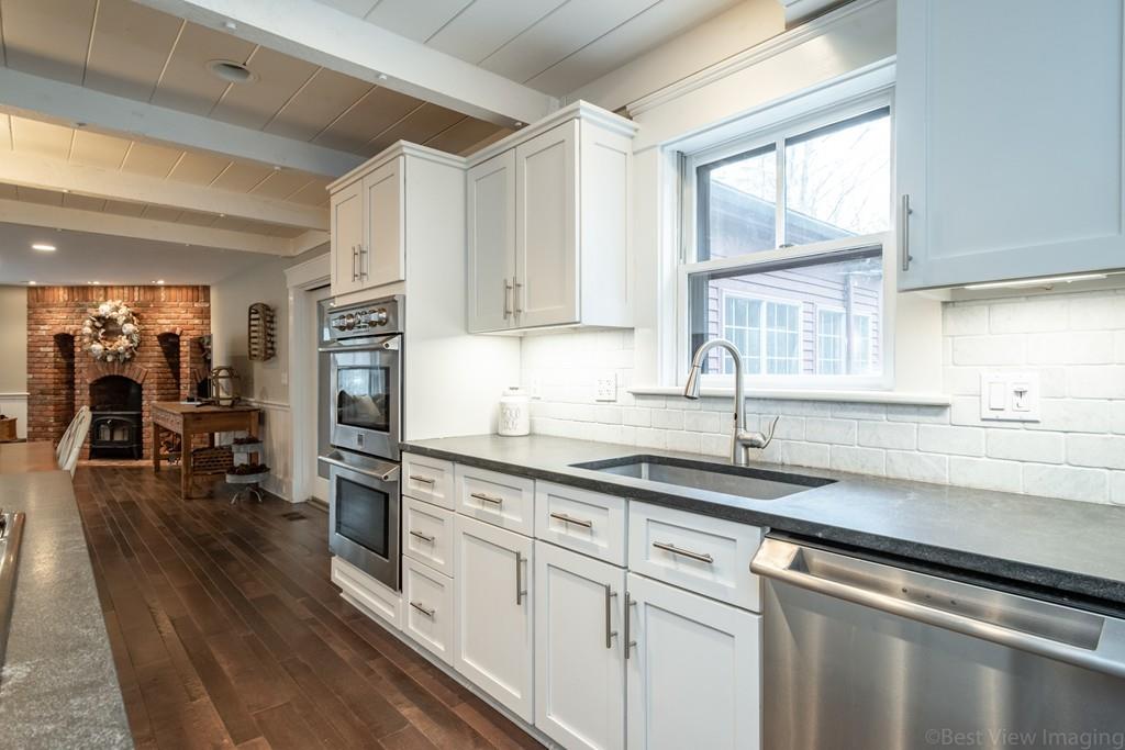 25 Crockett Road Upton, MA 01568 - Photo 13 of 39 a kitchen with stainless steel appliances granite countertop a sink dishwasher a stove and white cabinets with wooden floor
