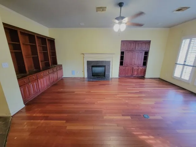 wooden floor fireplace and windows in an empty room