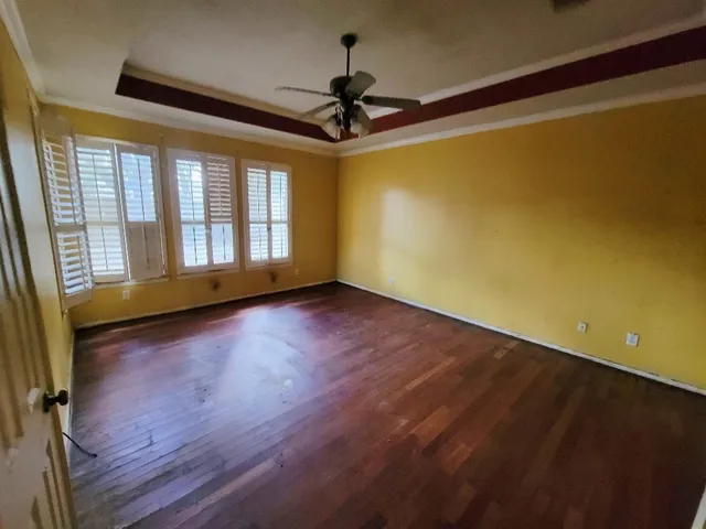 a view of empty room with wooden floor and fan