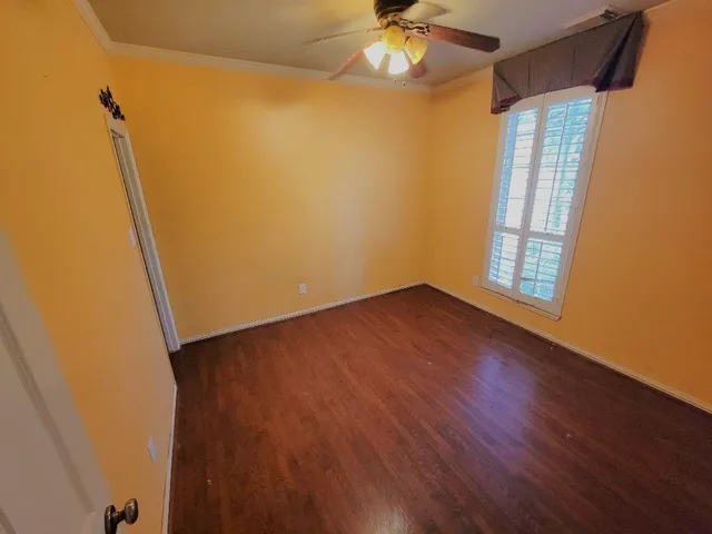 a view of an empty room with a window and wooden floor