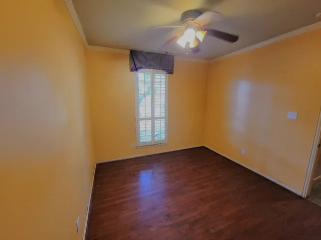 a view of an empty room with window and wooden floor