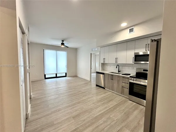 a large kitchen with stainless steel appliances granite countertop a large counter top a sink and a refrigerator