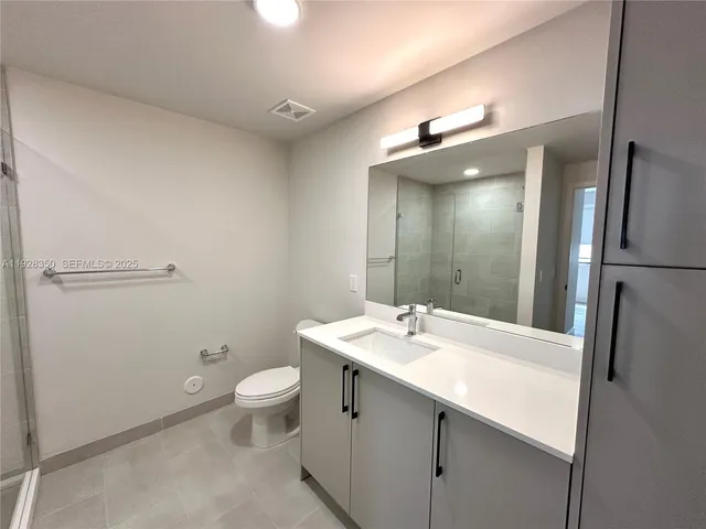 a bathroom with a sink a toilet a mirror and shower