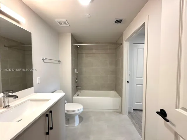 a bathroom with a bathtub shower sink vanity mirror and toilet