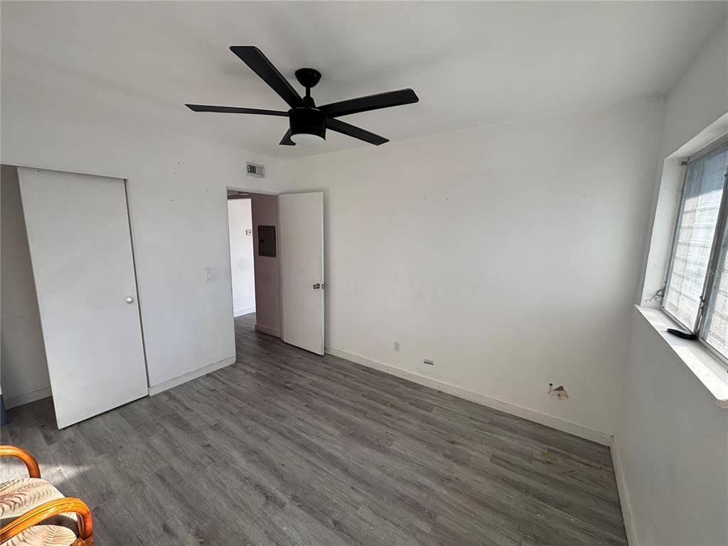 4061 55th Way North, Unit 1042 Kenneth City, FL 33709 - Photo 11 of 18 an empty room with wooden floor cabinet and windows