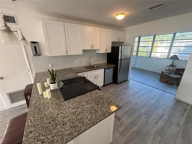 a kitchen with granite countertop a stove refrigerator and wooden floor