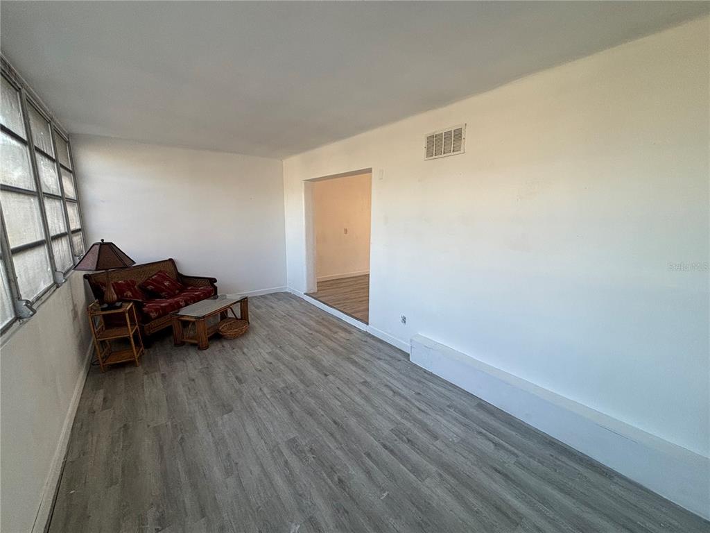 4061 55th Way North, Unit 1042 Kenneth City, FL 33709 - Photo 8 of 18 an empty room with wooden floor and a window