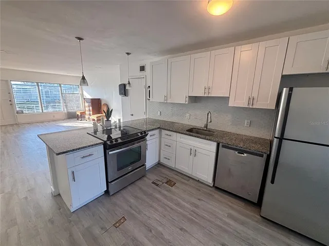 a kitchen with stainless steel appliances granite countertop a sink a stove a refrigerator and cabinets