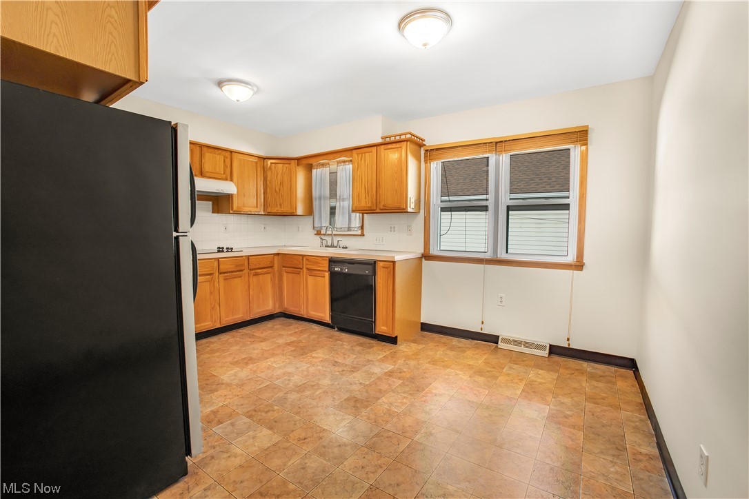 1590 Norledge Road Akron, OH 44305 - Photo 10 of 21 Kitchen featuring light tile flooring, sink, black dishwasher, backsplash, and fridge