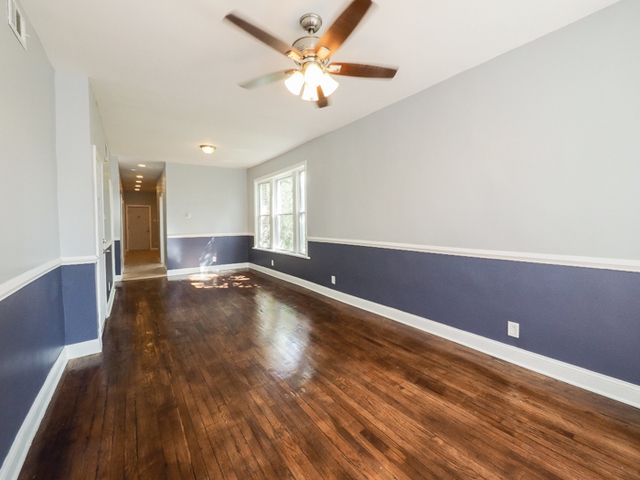 a view of room with a ceiling fan and wooden floor