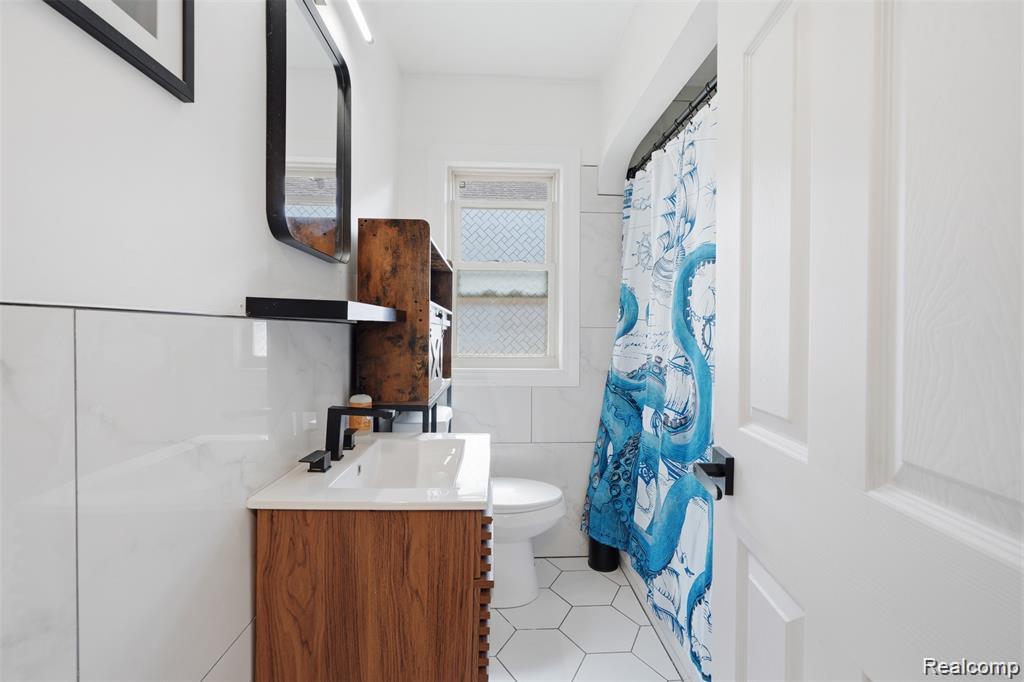 4612 Balfour Road Detroit, MI 48224 - Photo 15 of 20 Full bathroom featuring a wood-finish vanity with an integrated sink, matte black faucet, and a wall-mounted mirror