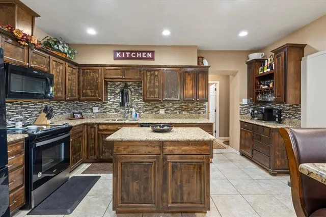 a kitchen with stainless steel appliances kitchen island granite countertop a stove a sink and a microwave