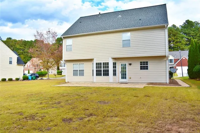 a front view of house with yard and trees in the background