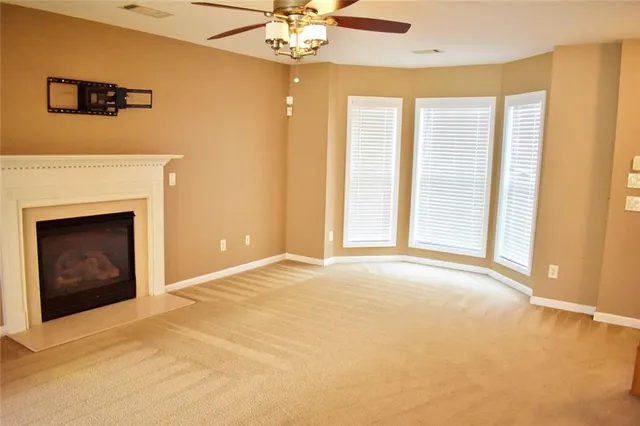 a view of an empty room with chandelier fan and fire place