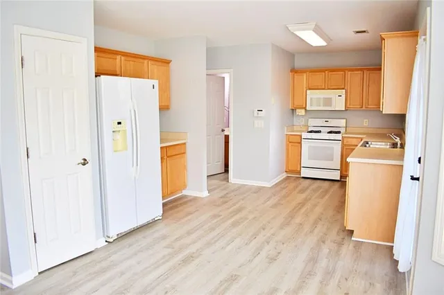 a view of a kitchen with wooden floor and a refrigerator