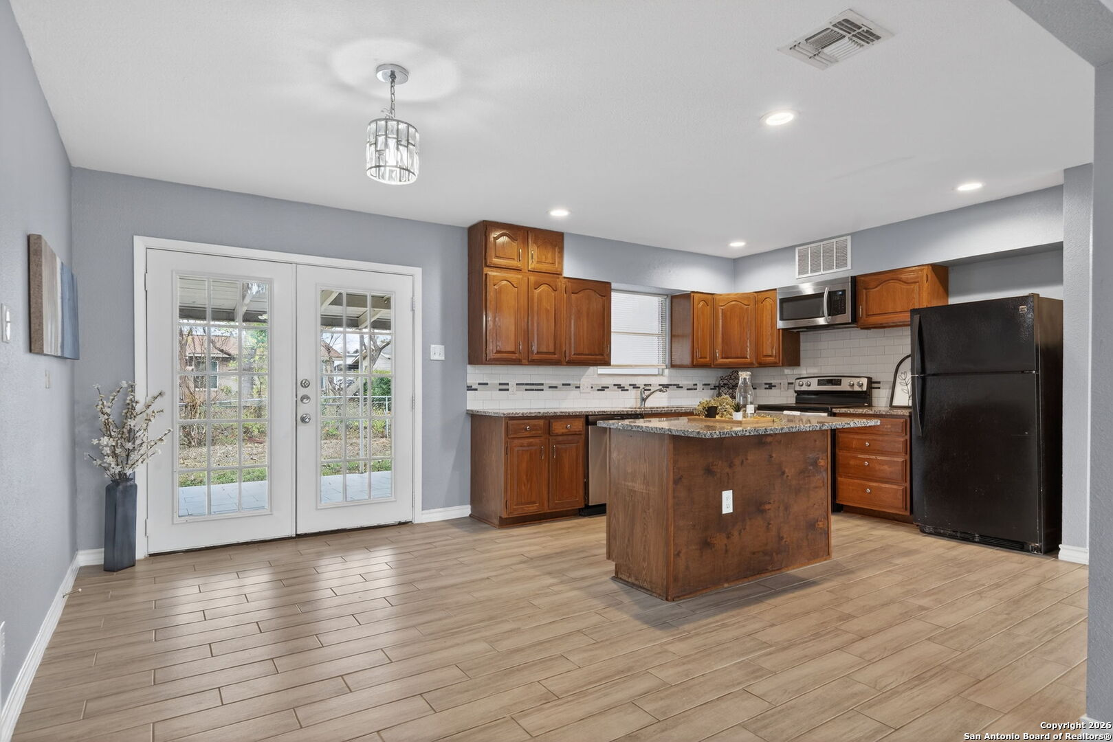 4531 Eisenhauer Road San Antonio, TX 78218 - Photo 16 of 32 a kitchen with stainless steel appliances granite countertop a refrigerator a stove top oven a sink and dishwasher with wooden floor