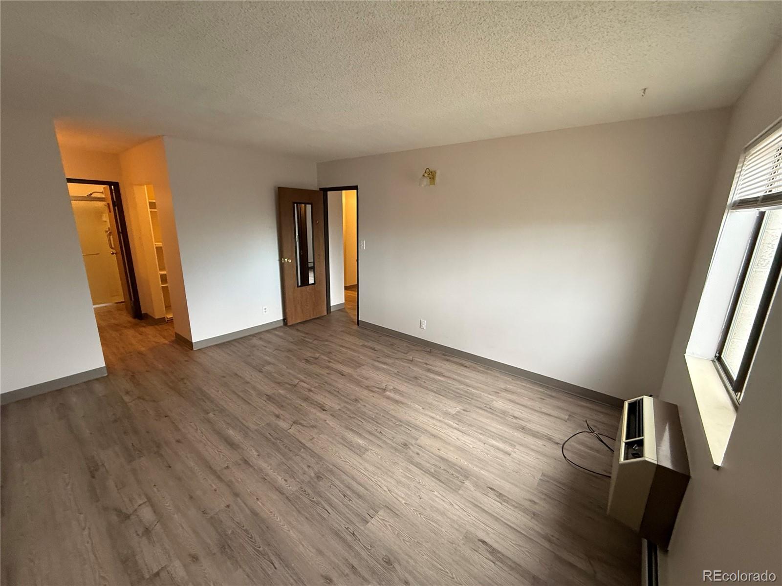 7780 West 38th Avenue, Unit 302 Wheat Ridge, CO 80033 - Photo 3 of 17 a view of an empty room with wooden floor and a window