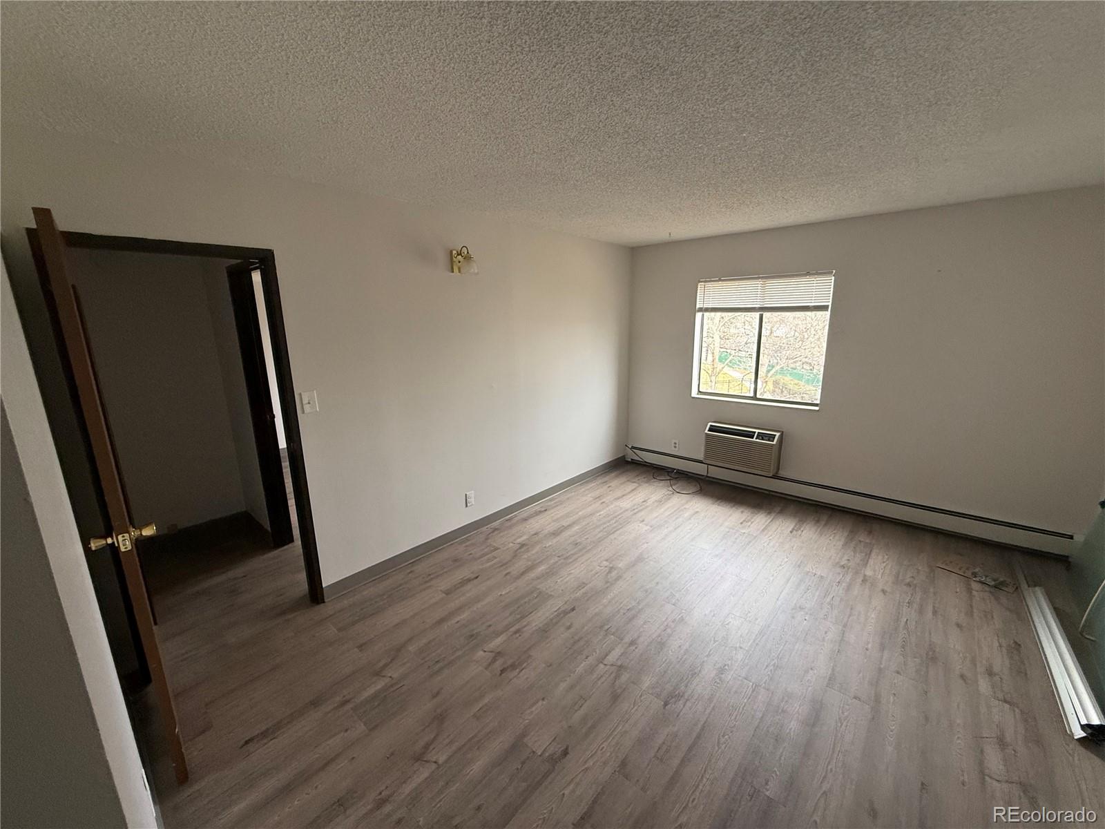 7780 West 38th Avenue, Unit 302 Wheat Ridge, CO 80033 - Photo 6 of 24 an empty room with wooden floor and windows