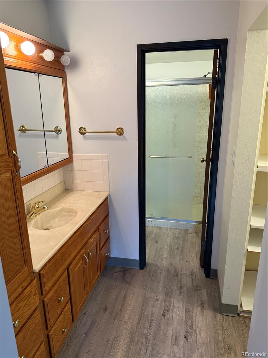 7780 West 38th Avenue, Unit 302 Wheat Ridge, CO 80033 - Photo 7 of 24 a bathroom with a sink a mirror and a shower