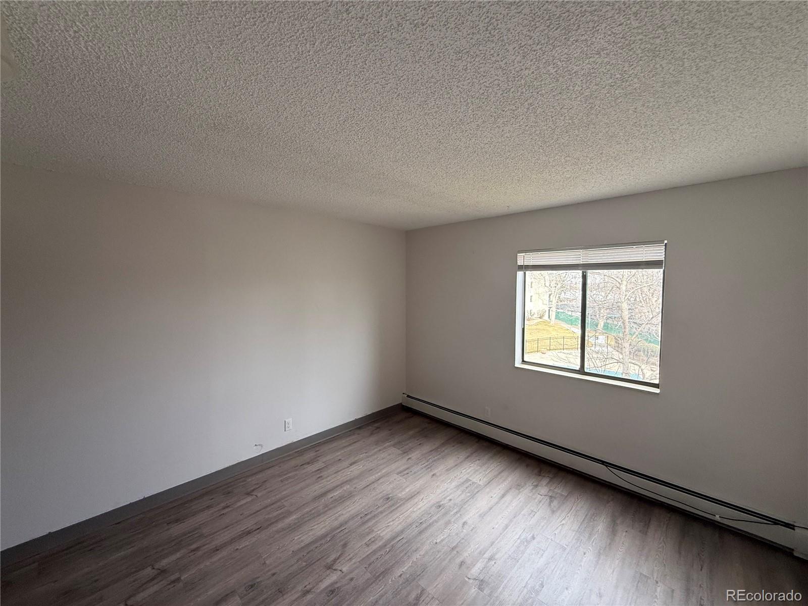 7780 West 38th Avenue, Unit 302 Wheat Ridge, CO 80033 - Photo 10 of 17 an empty room with wooden floor and windows